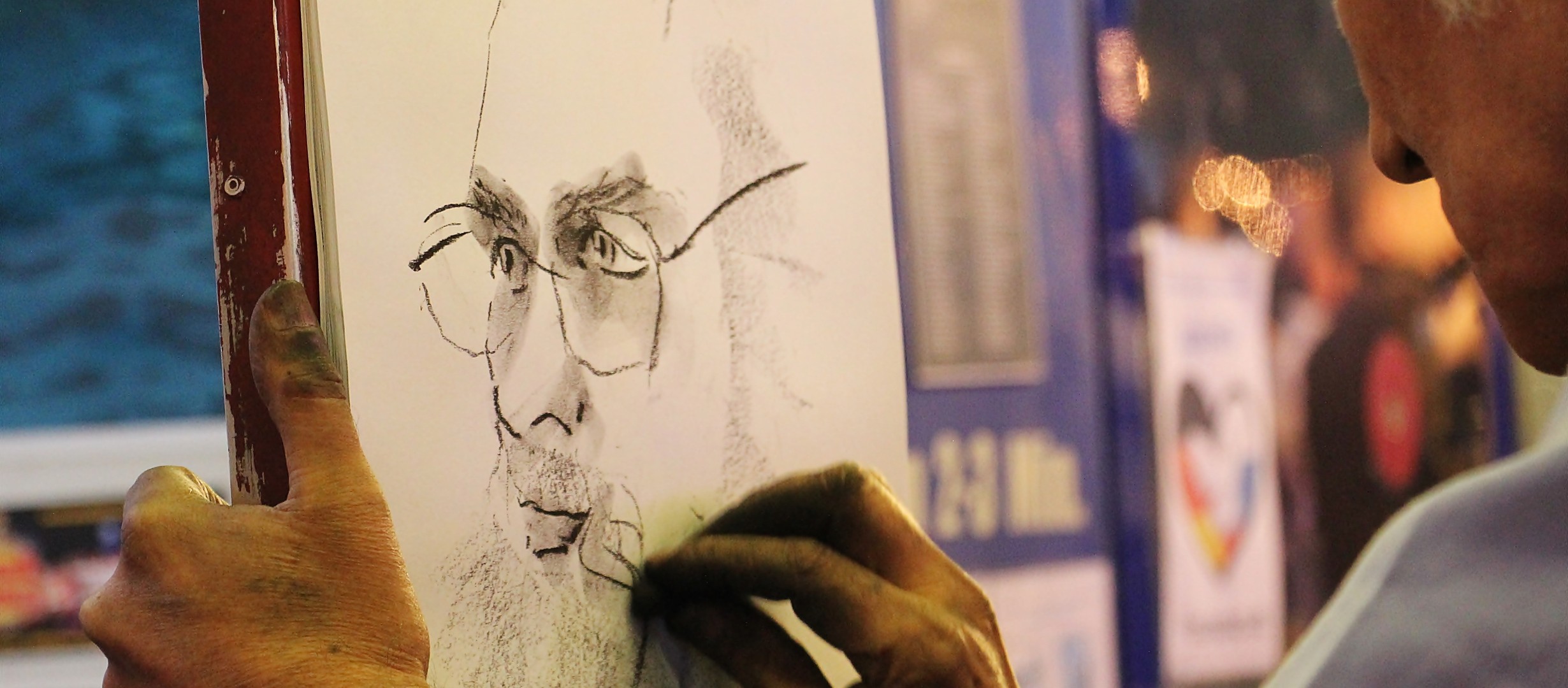 Man in a life drawing class drawing a face of a man in glasses