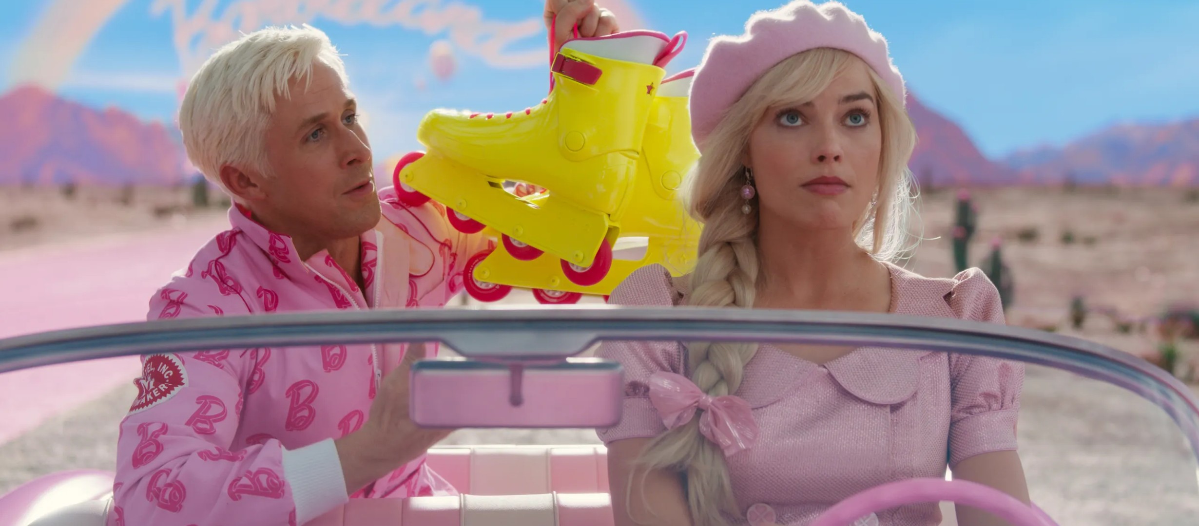 Margot Robbie as Barbie and Ryan Gosling as Ken. They are in a car and Ryan is showing Margot a pair of bright yellow roller skates