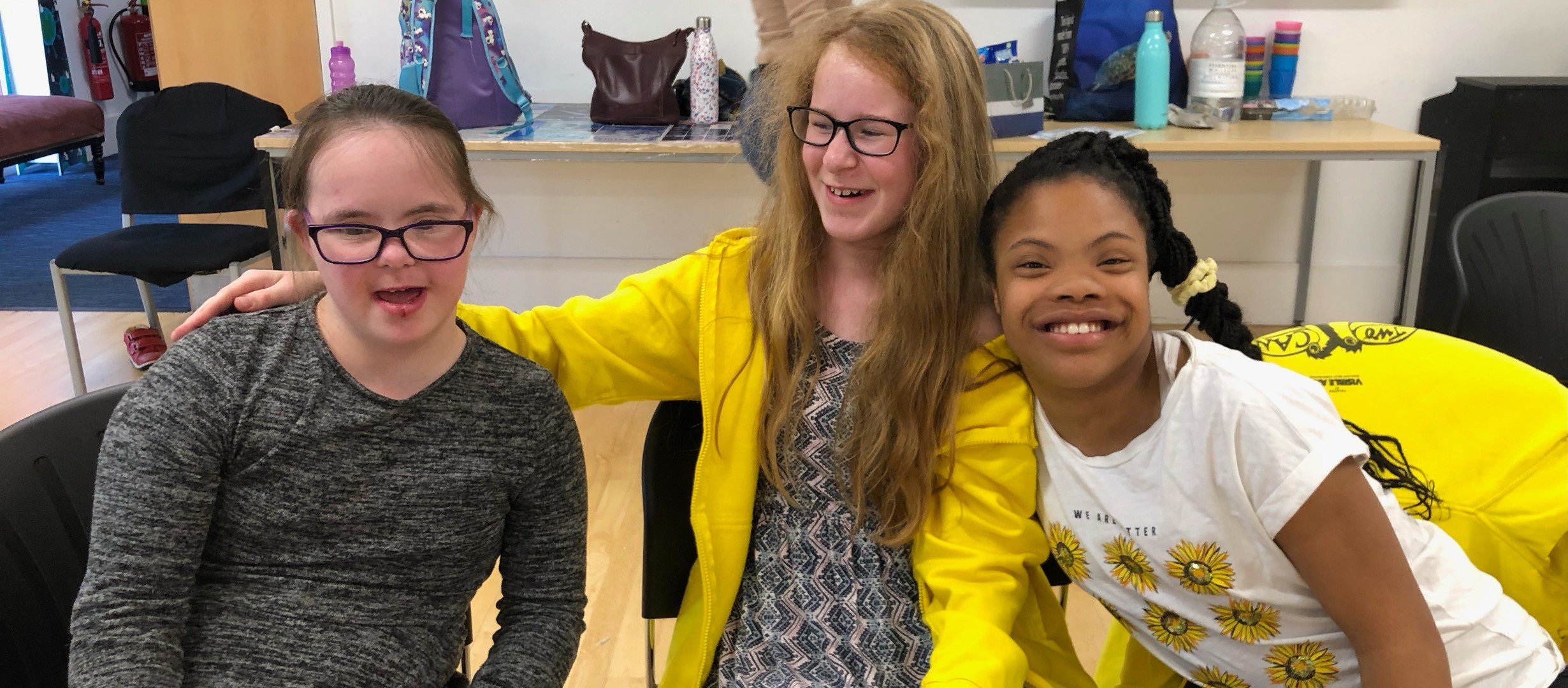 Three young people seated facing the camera and smiling