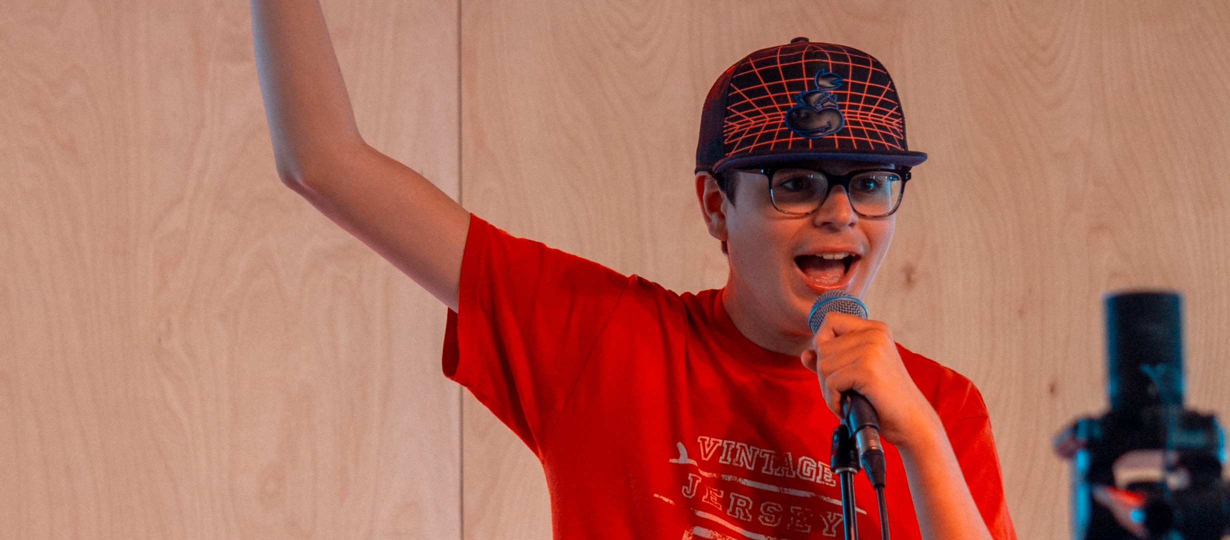 Young man holding a microphone with his right arm in the air