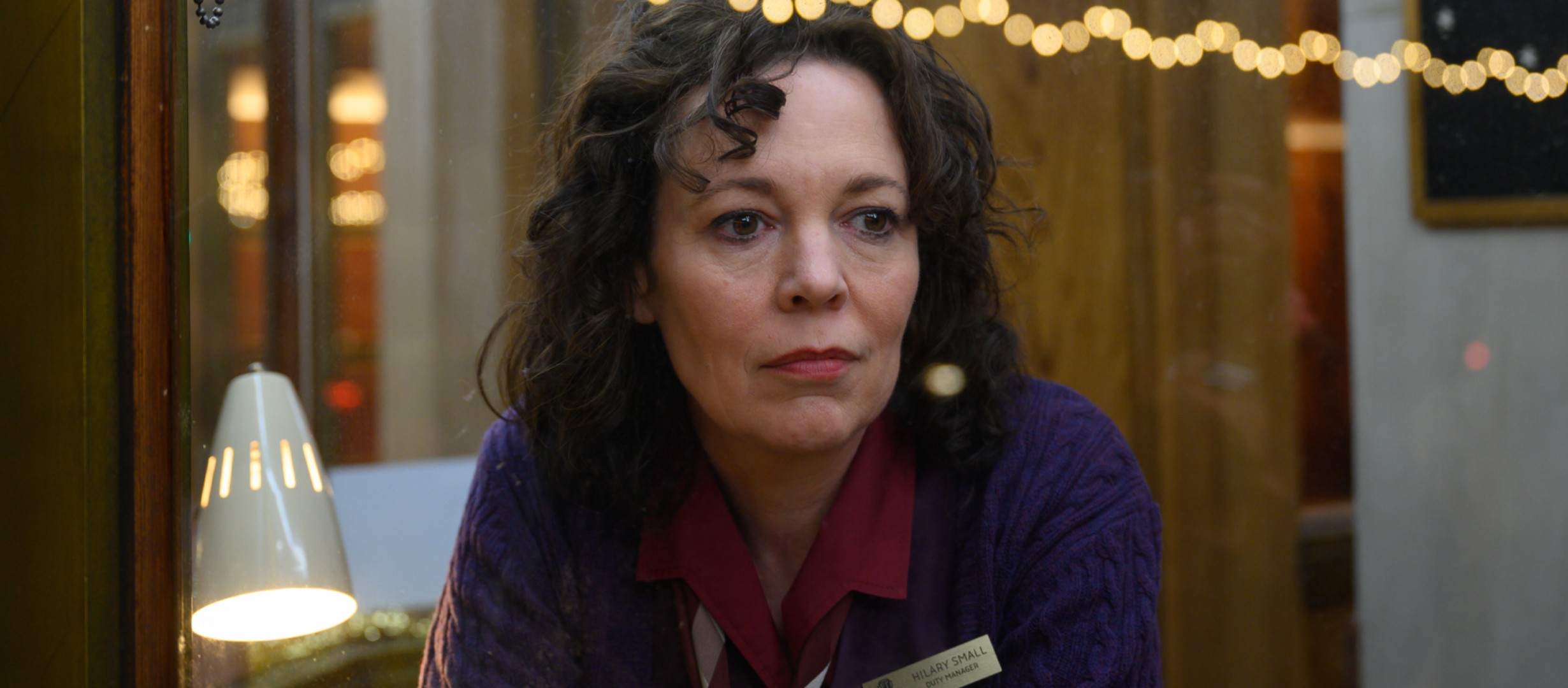 A lady behind a window with fairy lights behind
