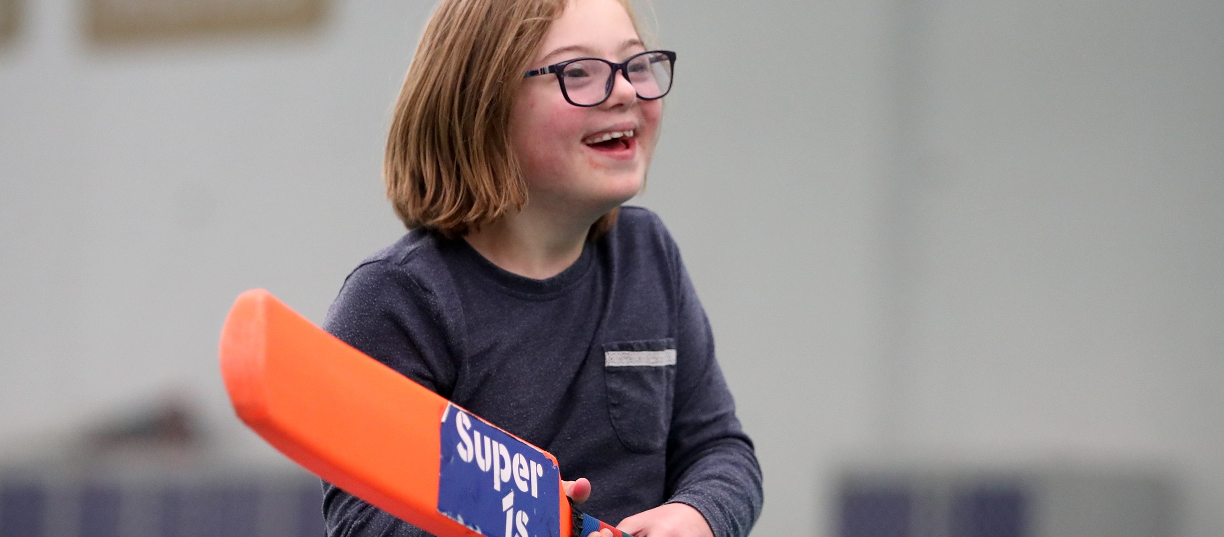 Young person holding orange cricket bat