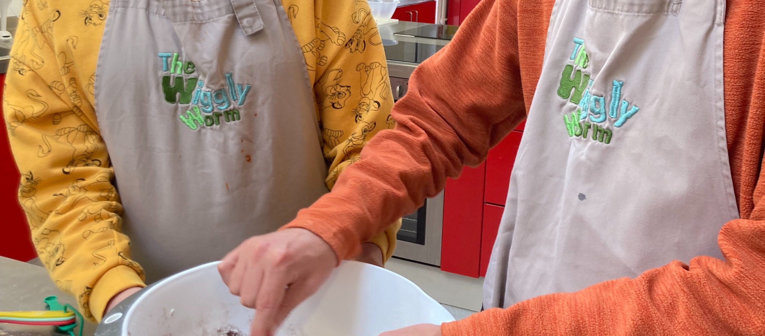 two people standing over a bowl of ingredients. one person is stirring
