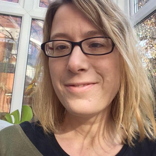 A photo of Sarah, a blonde woman, wearing glasses, smiling at the camera.