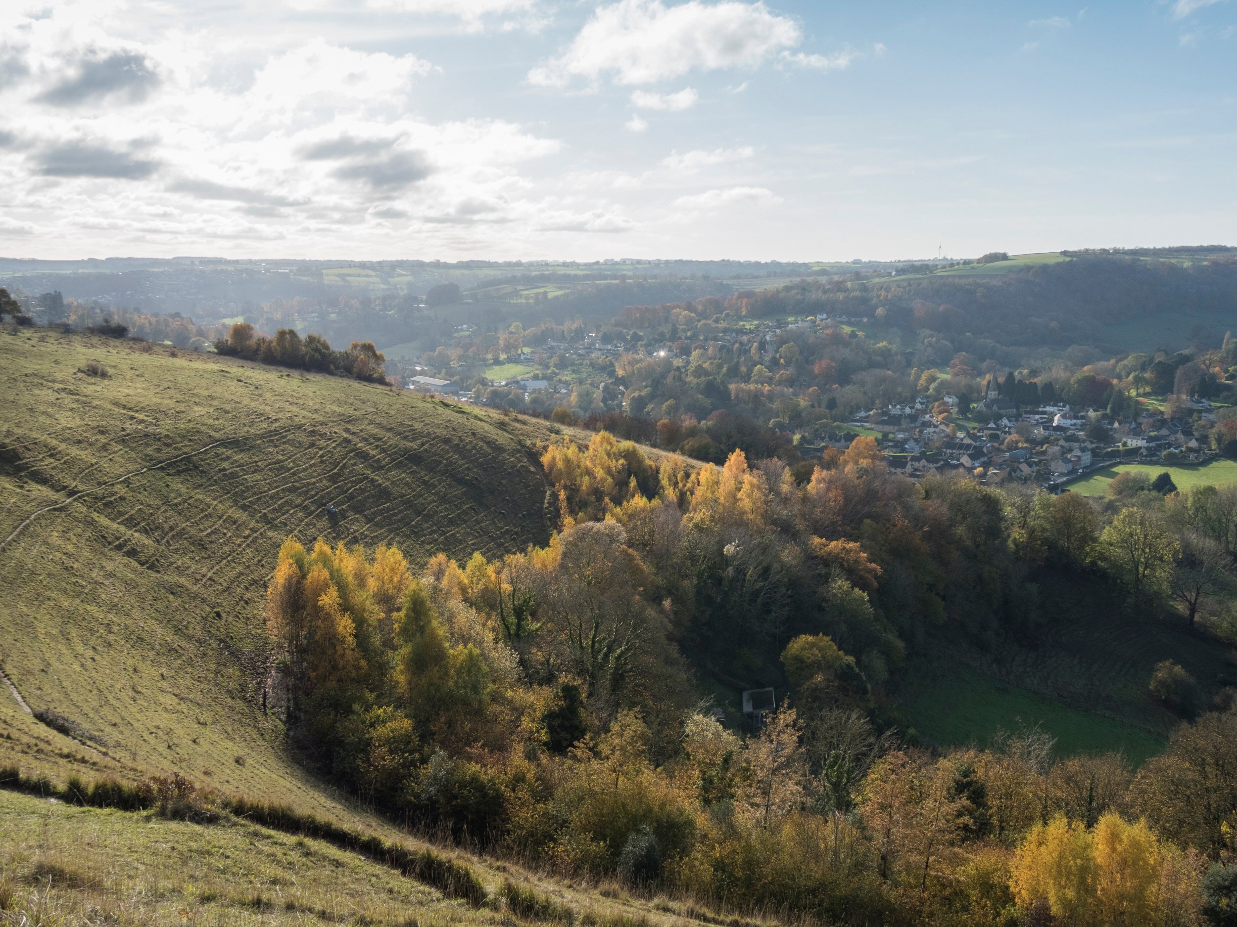 A landscape photo showing clouds above the green hills of Rodborough Common