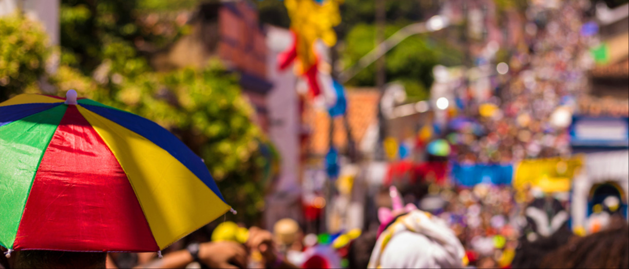 This is a photograph of a street festival. There is a colourful umbrella in the left corner