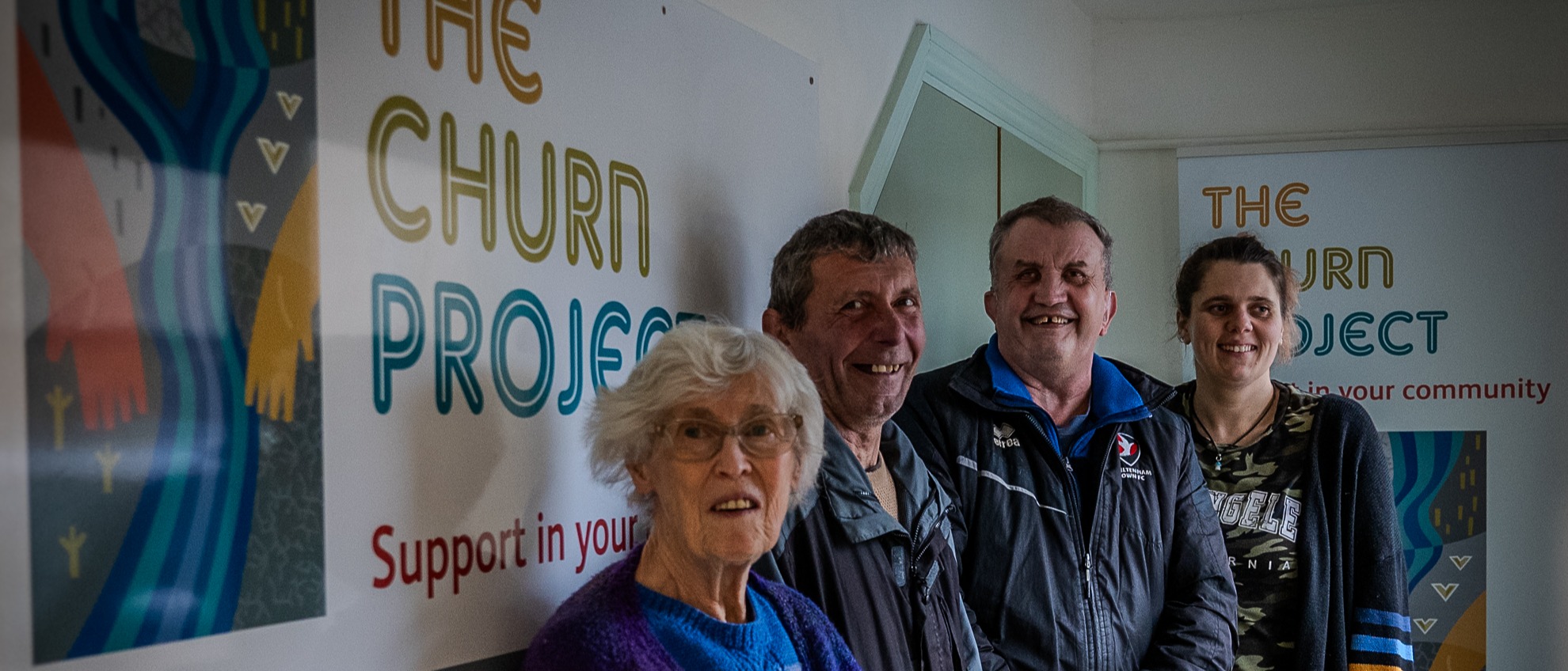 Four of our Churn Project participants standing in our offices in front of our logo