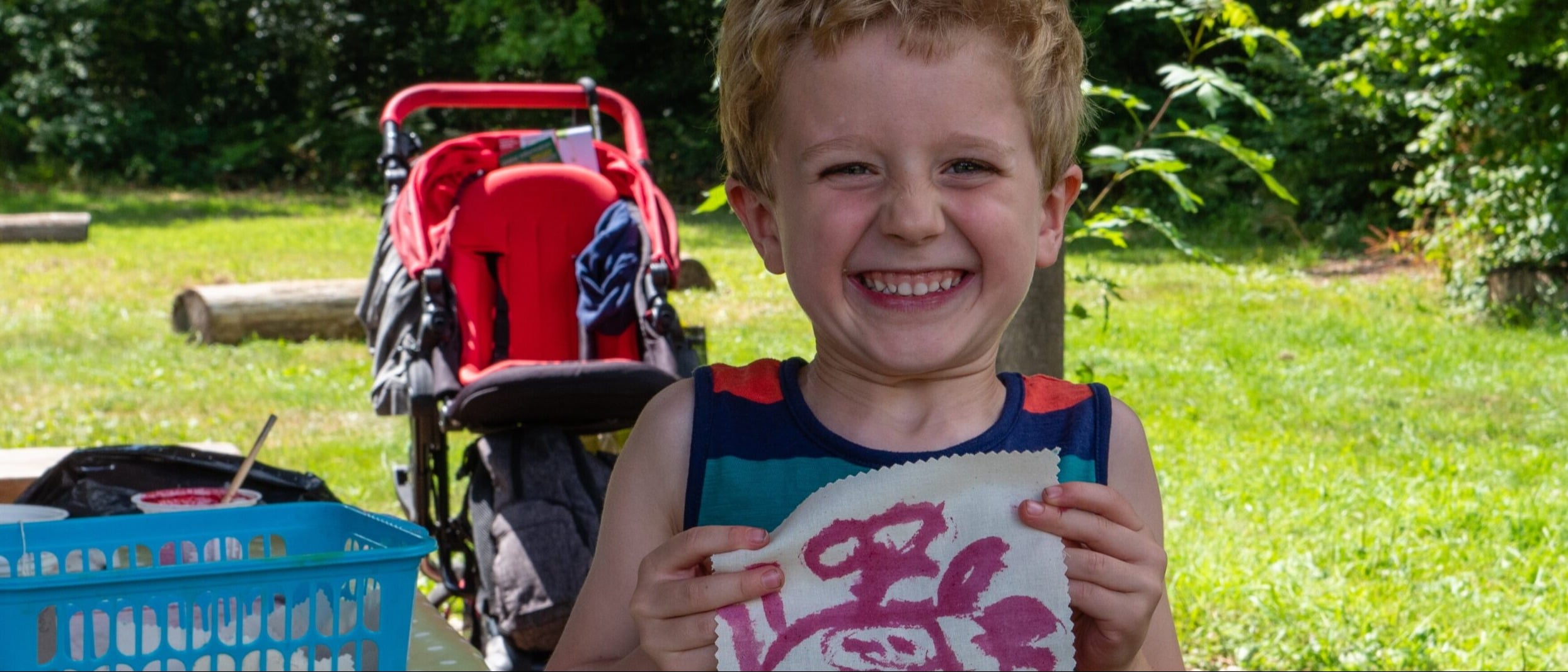 child holding up a painting outside on summers day