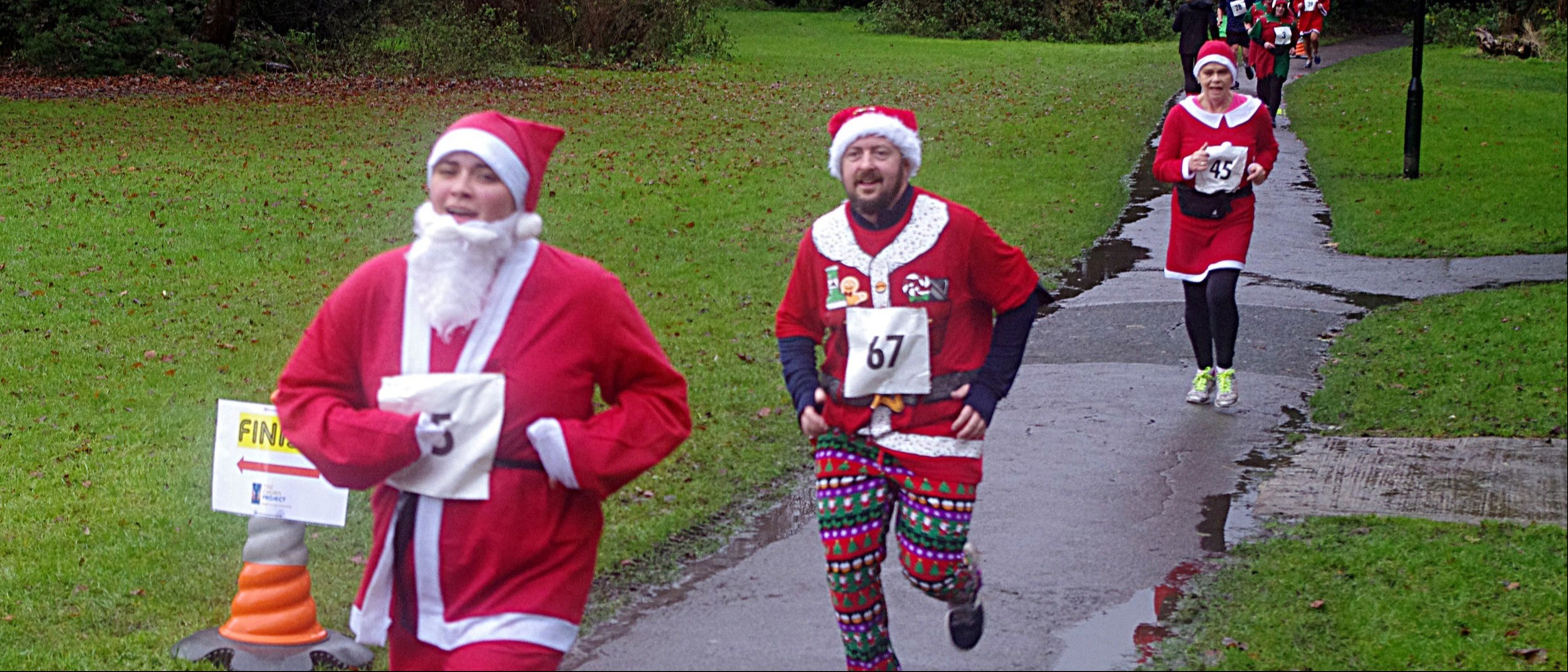 Three people running dressed in Santa Suits